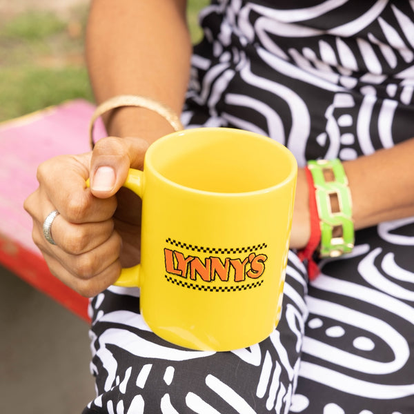 yellow mug with Lynny's logo in the hand of a person