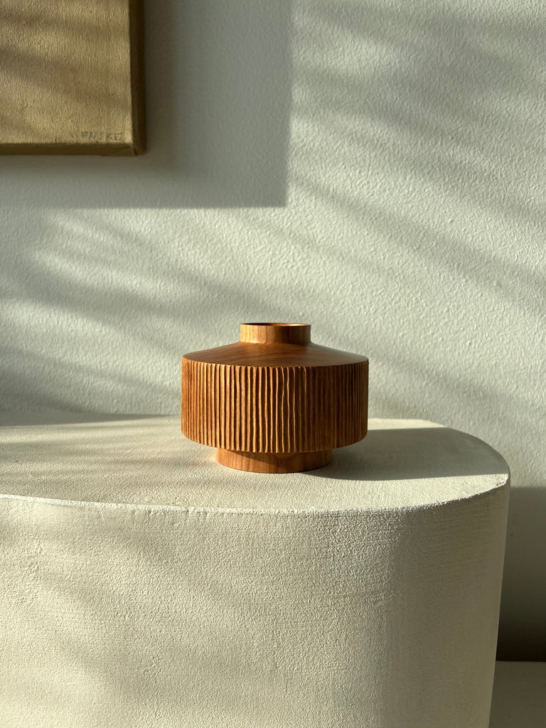 wooden carved vase sittin on white ledge