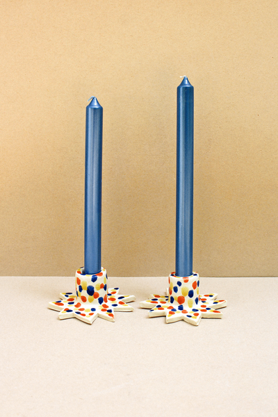 pair of mulicolor star shaped ceramic candleholders with blue candles